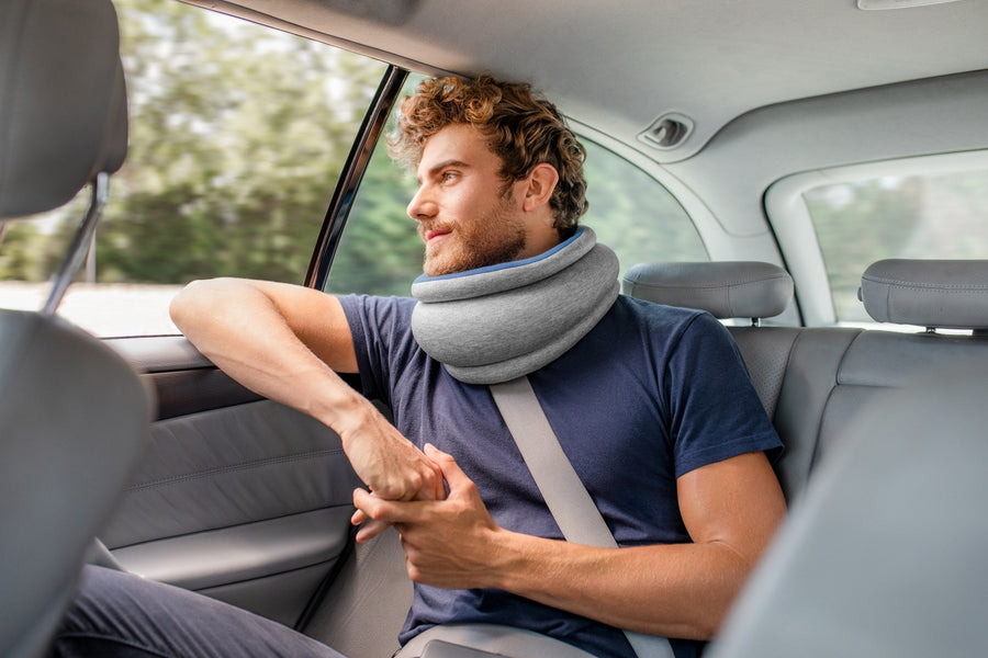 車の後席で Light Versatile Pillow を首に掛けて窓の外を見る男性
