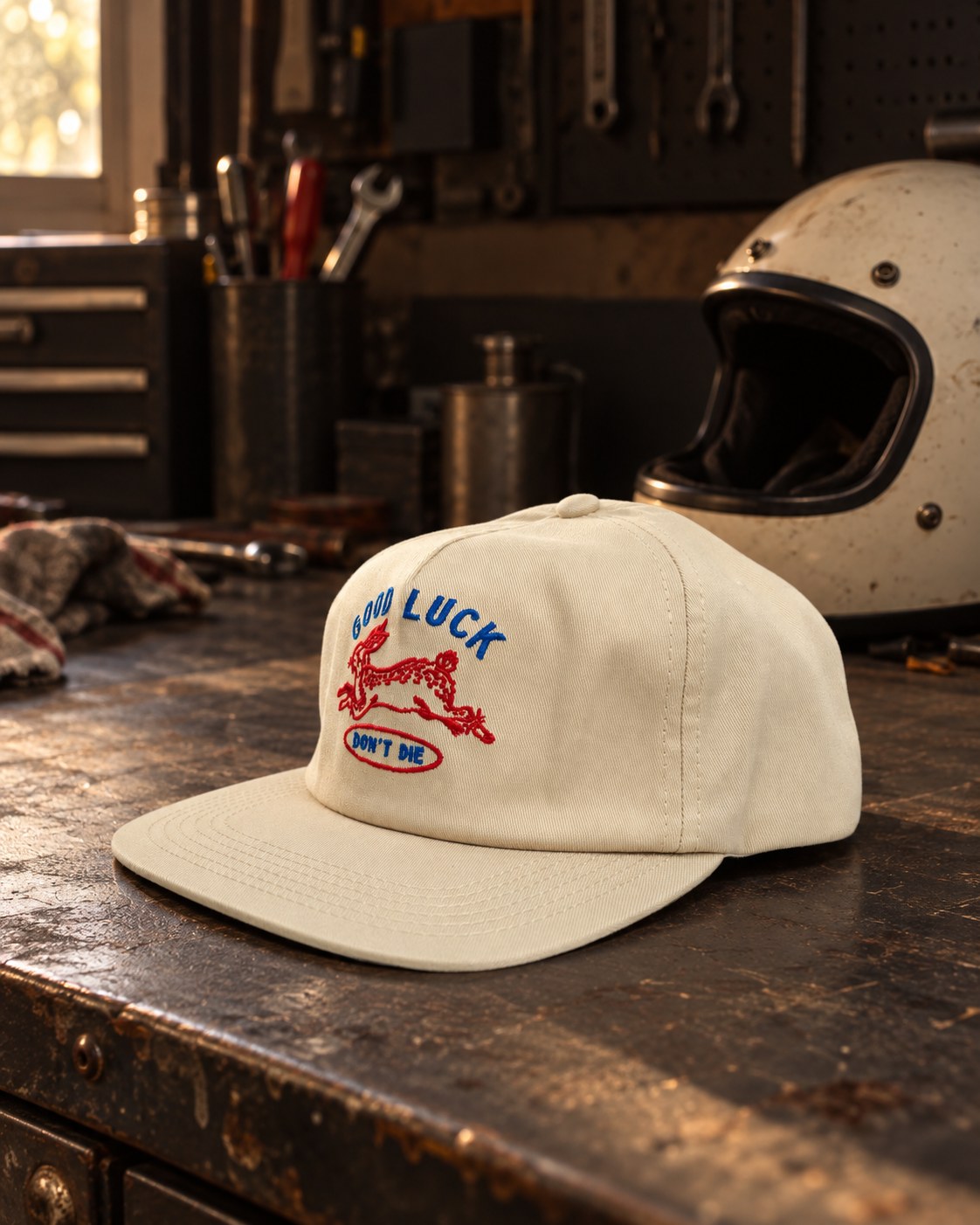 作業台に置いた Good Luck Hat と後ろのヘルメット