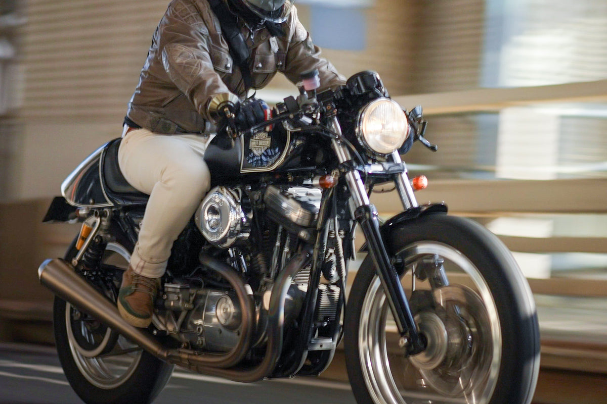 夕方の街を走るオートバイと、革のジャケットのライダー
