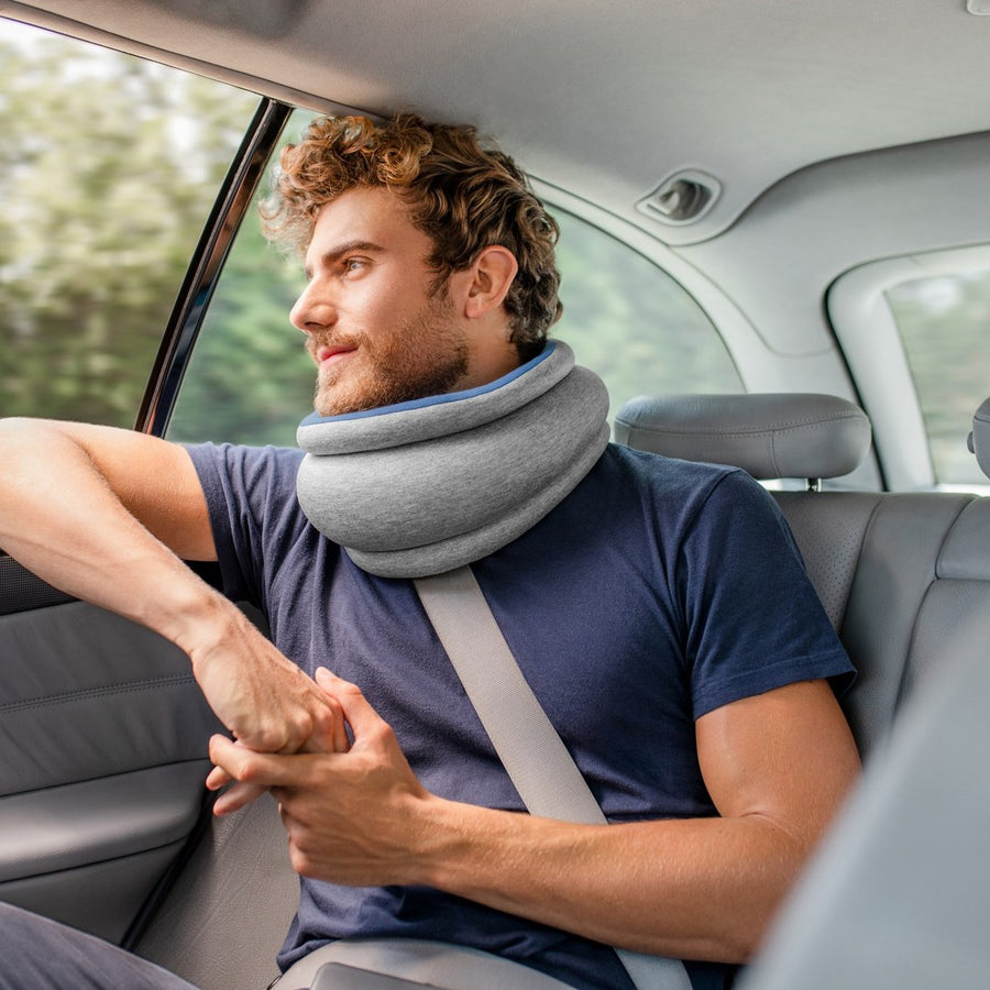 車の後席で Light Versatile Pillow を首に掛けて窓の外を見る男性